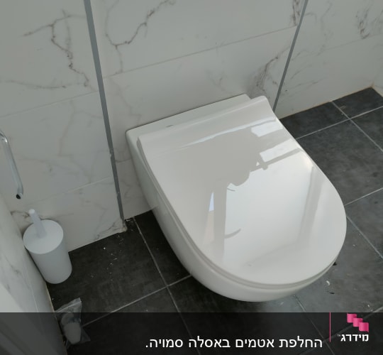 אסלה תלויה עם מברשת שירותים על רצפת אריחים